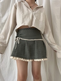 a woman is laying on a bed wearing a shirt and skirt