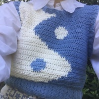 a woman wearing a blue and white crochet vest